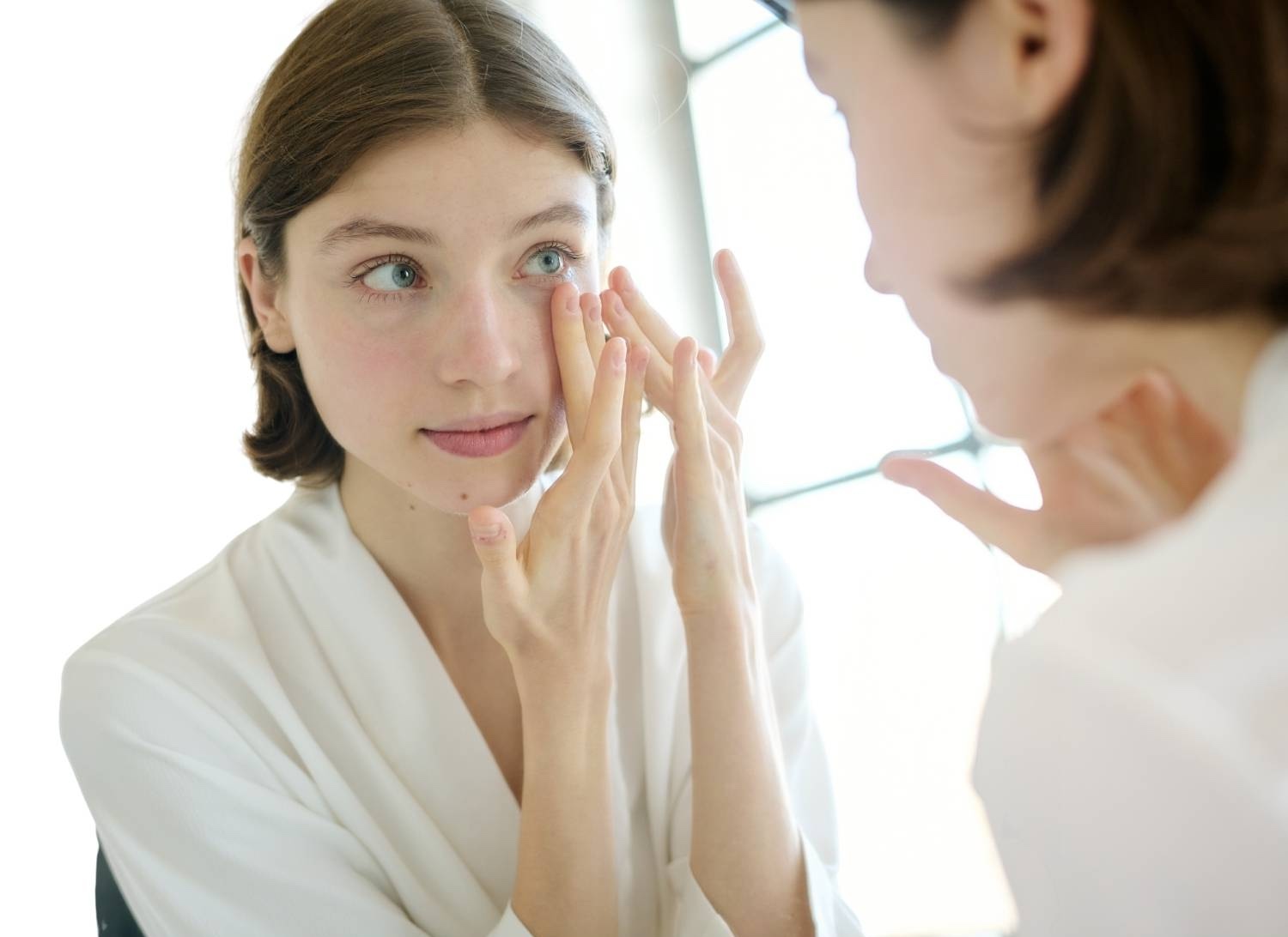Applying gentle pressure to the area around the eyes, in front of a mirror
